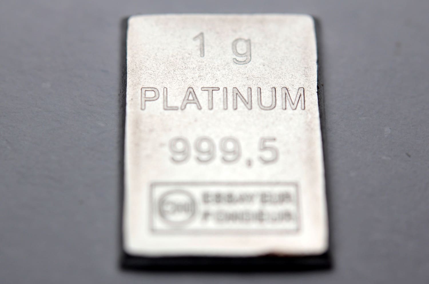 A one-gram platinum bar against a grey background